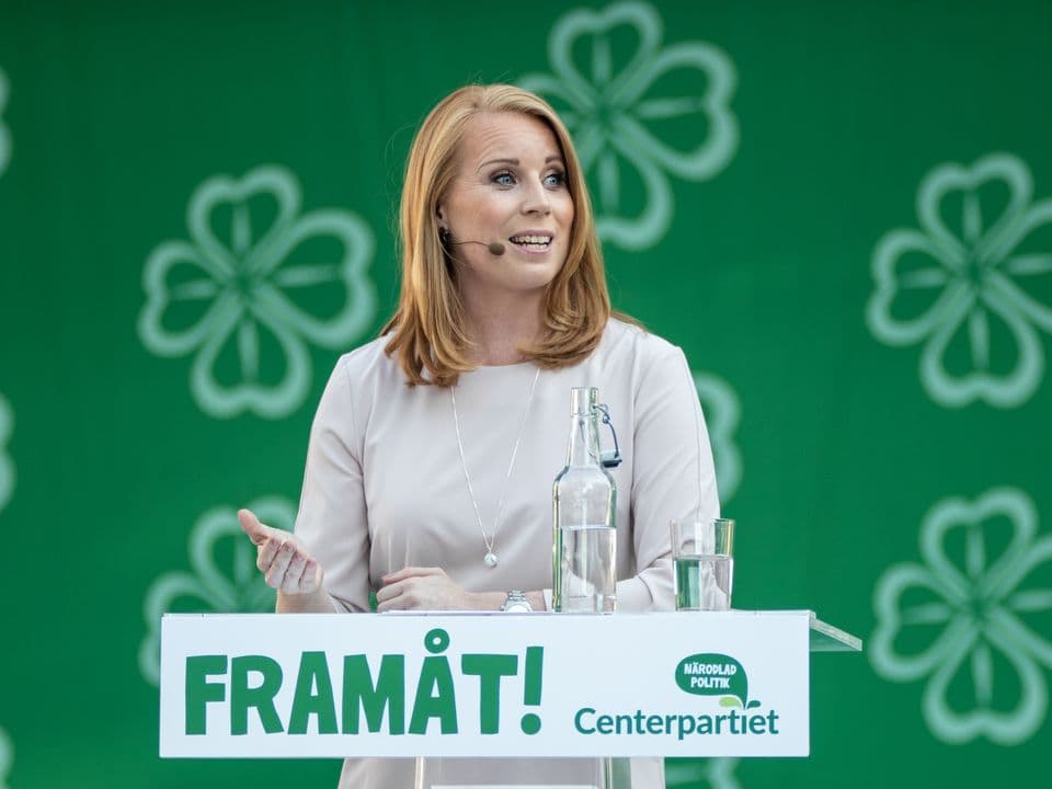 Annie Lööf speaking in front of a green Centre Party backdrop with the slogan Framåt