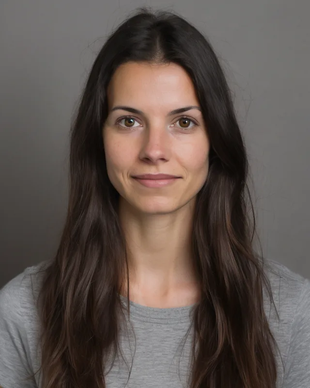 Front-facing photo of a woman with long dark hair in a grey t-shirt against a grey wall